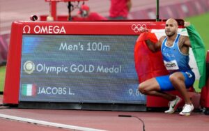 Marcell Jacobs posa davanti al tabellone dello Stadio Nazionale di Tokyo dopo l'oro vinto nei 100 Metri